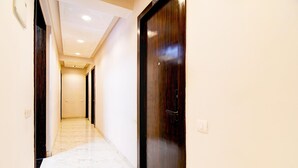 A hallway with a marble floor, wooden doors, and recessed ceiling lighting. - Premium New Krish Residency (Barasat)