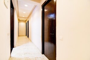 A hallway with a marble floor, wooden doors, and recessed ceiling lighting. - Premium New Krish Residency (Barasat)