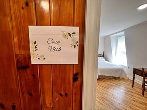 A room with a wooden door, a bed with white bedding, and a small wooden table.