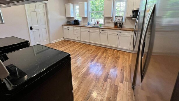 A modern kitchen with a black stove, white cabinets, and a stainless steel refrigerator. - Fiddler's Roost At The Washington Inn (Fries)
