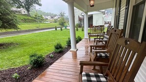 Une véranda en bois avec des bancs, une lanterne suspendue et une vue sur un paysage verdoyant.