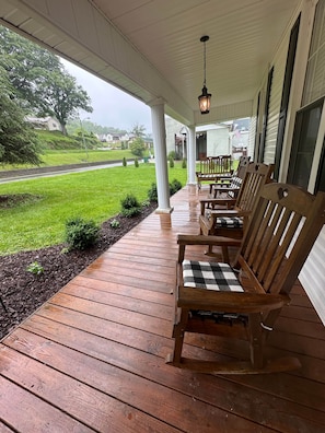 A wooden porch with benches, a hanging lantern, and a view of a green landscape.