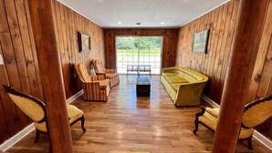 Een kamer met houten wanden en vloeren, een bank, twee fauteuils en een salontafel.