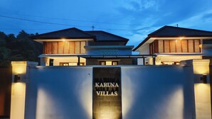 En moderne villa med en markant indgangsport, hvor der står 'Karuna Villas'.