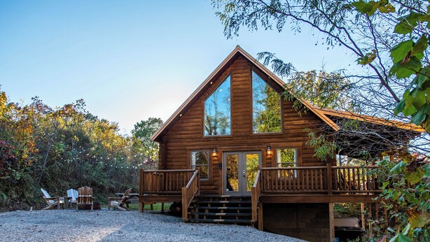 Une cabane en bois dotée d’une terrasse, d’une allée en gravier et d’un espace salon extérieur.