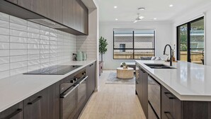 Une cuisine moderne dotée d’un îlot central, d’une grande fenêtre et offrant une vue sur un bâtiment en briques.