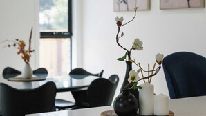 Un espace repas moderne avec un îlot central, des chaises noires et un vase rempli de fleurs.