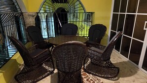 A dining area with a round table and six wicker chairs, a yellow wall, and a view of a staircase. - Este es el Appartamento de 3 Habitación (Pedro Brand)