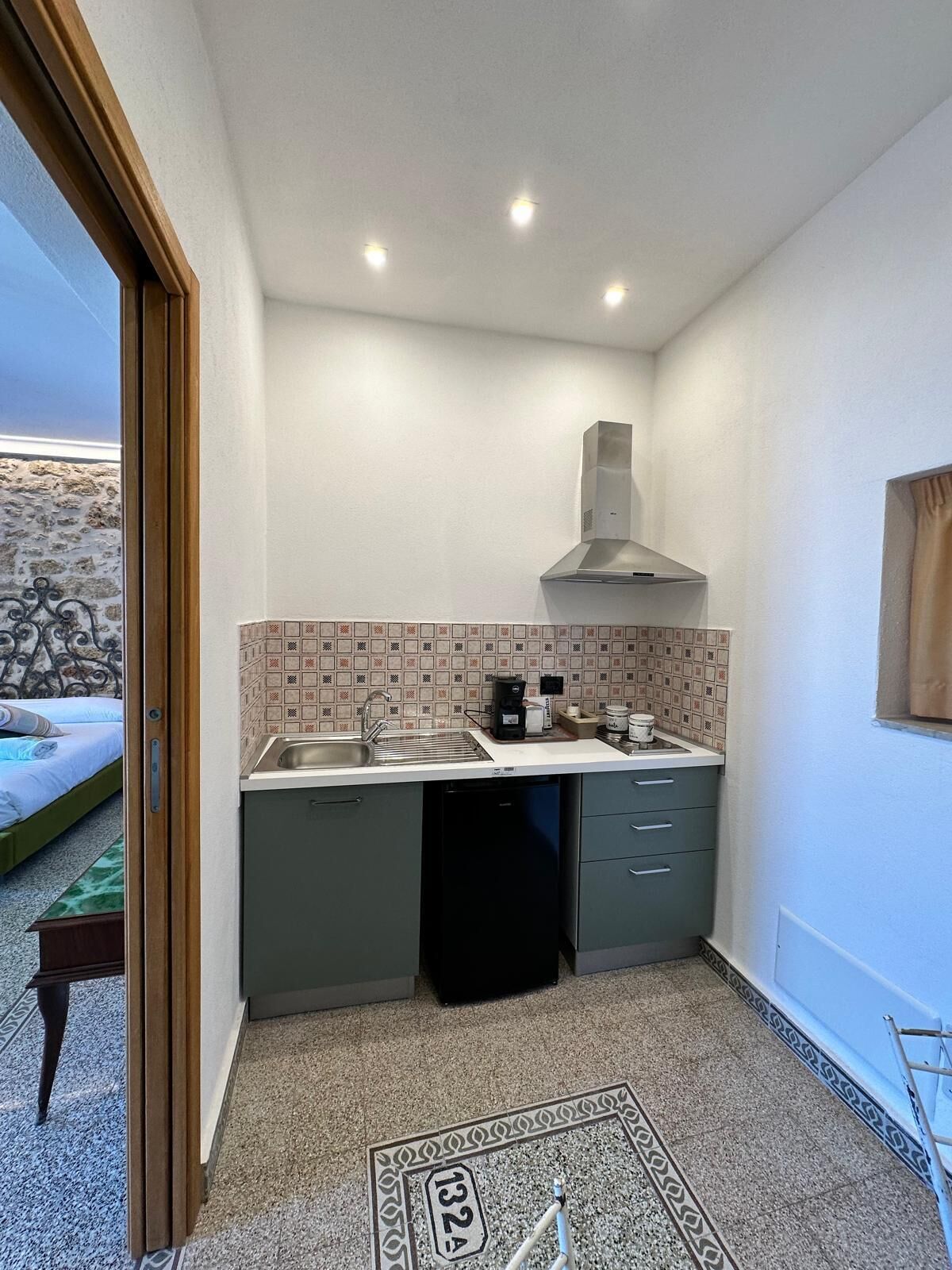 A compact kitchen with a sink, stove, and a ventilation hood.