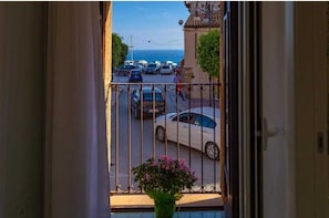 A balcony with a view of parked cars and a building with a tiled roof. - Torre del Pardo Guest House (Sciacca)