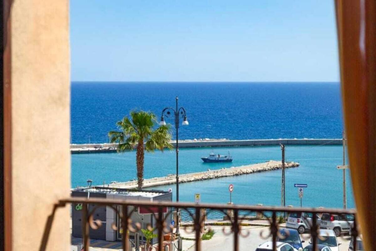 Un balcón con vista al mar, una palmera y un bote.