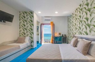 Una camera d'albergo con un letto, una scrivania, una sedia e un balcone con vista.