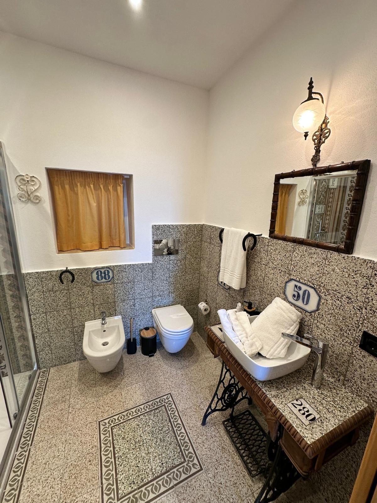 Une salle de bain équipée d’un bidet, de toilettes, d’un lavabo et d’un miroir.