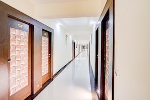 A long, well-lit hallway with doors marked with numbers, leading to rooms.