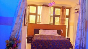 Un dormitorio con cama, cortinas, una ventana y aire acondicionado instalado en la pared.