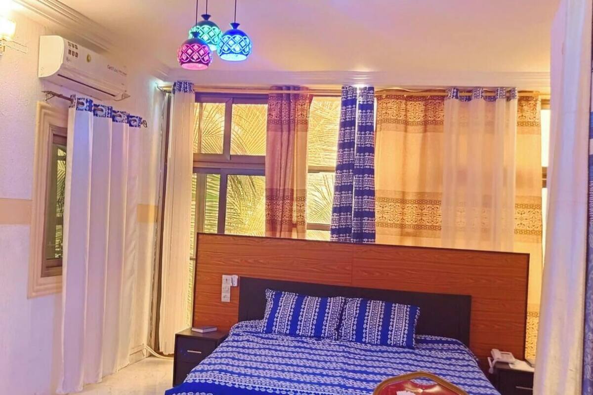 Une chambre à coucher avec une tête de lit en bois, une couvre-lit à motifs et des rideaux aux couleurs bleu et or.