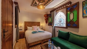 A hotel room with a bed, a green sofa, a wooden wardrobe, a nightstand, a decorative ceiling, and a stained glass window. - RIAD SULTAN CHEFCHAOUEN (Chefchaouen)
