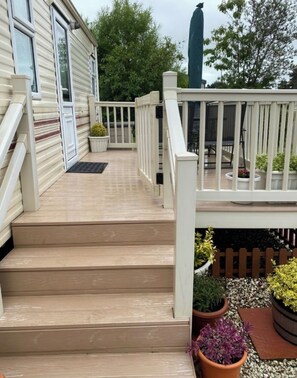 A wooden deck with steps leading to a white railing, surrounded by potted plants and a fence. - Sea View Retreat (Port Seton)