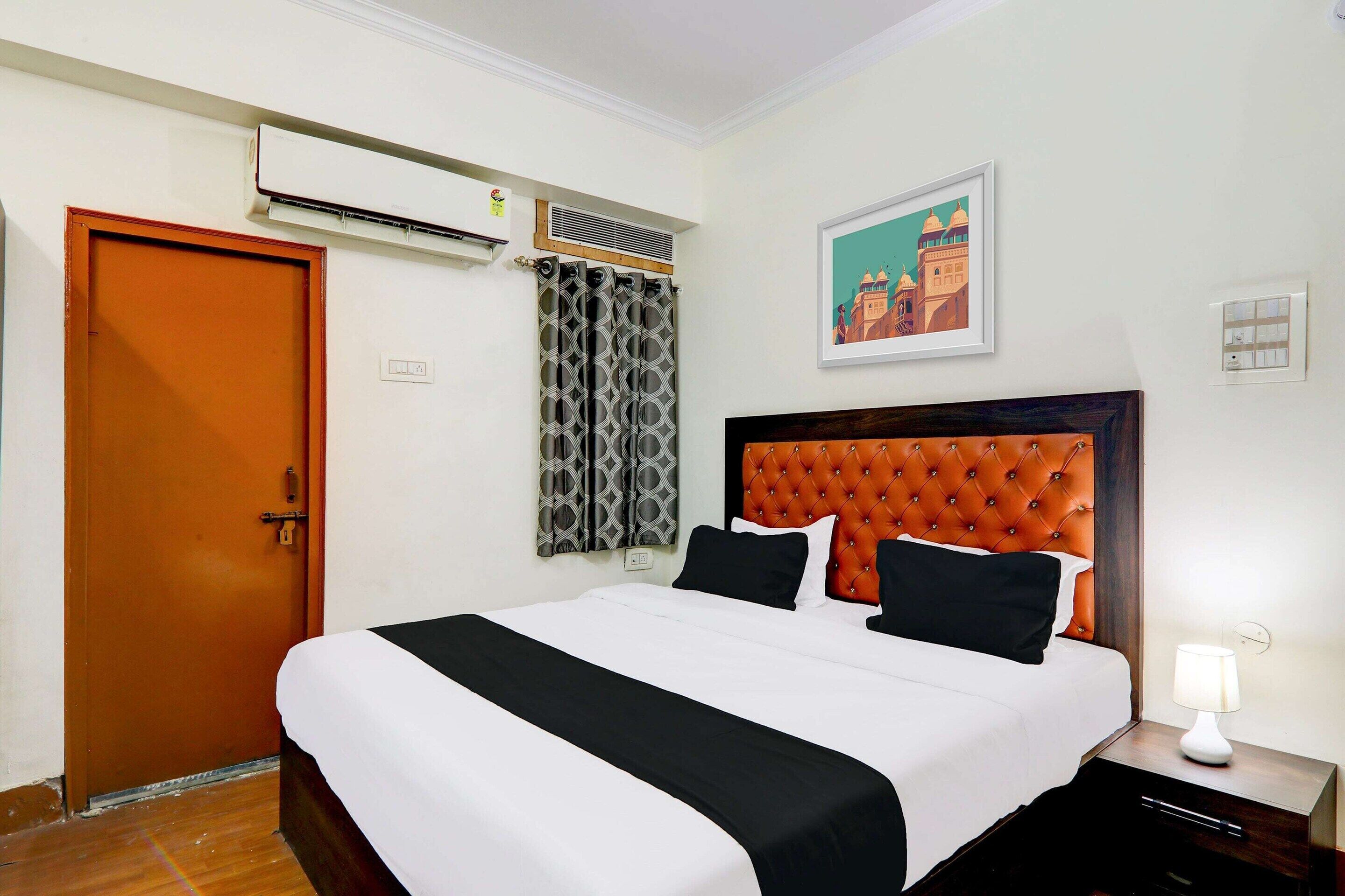 Camera d'albergo con un letto, un comodino, un condizionatore d'aria, una porta e un quadro appeso al muro.