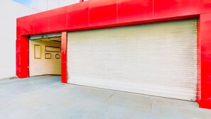 A red building with a closed shutter door and a visible entrance. - Super Deluxe Room Alambagh BM Palace (Lucknow)