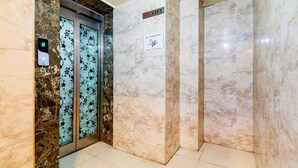 An elevator with a digital display, a non-smoking sign, and marble walls. - Super Deluxe Room Alambagh BM Palace (Lucknow)