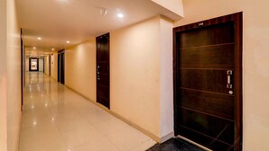 A long, well-lit hallway with doors on both sides, leading to rooms. - Super Deluxe Room Alambagh BM Palace (Lucknow)