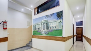 Corredor com extintor, escada e quadro de um edifício.
