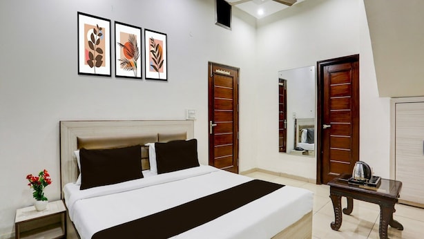 Quarto com cama, mesas de cabeceira, ventoinha no teto, espelho e quadros nas paredes.