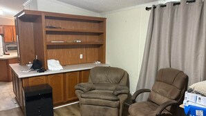 Una oficina en casa con un escritorio, dos sillas, una estantería y un archivador pequeño.