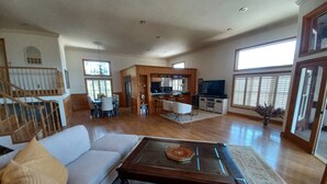 Amplia sala de estar con piso de madera, un sofá, una mesa de centro y una zona de cocina al fondo.