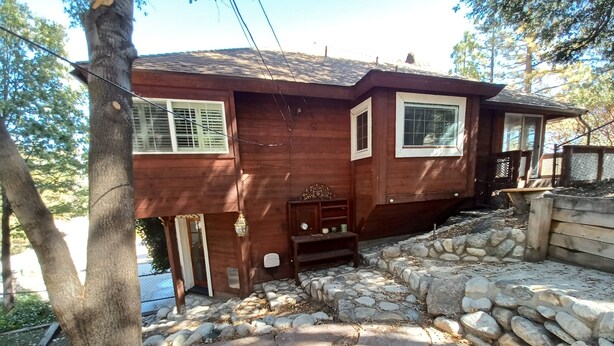 Una casa de madera con un sendero de piedra que lleva a la entrada, una banca y una pequeña mesa con un farol.