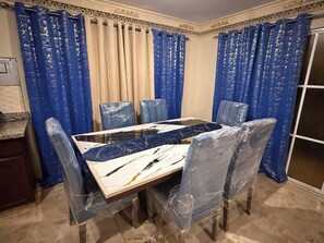 A dining area with a table, chairs, and blue curtains. - Este es el Appartamento de 2 Habitation (Pedro Brand)