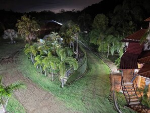 A nighttime view of a landscaped garden with palm trees, a pathway, and a building with a red roof. - Este es el Appartamento de 2 Habitation (Pedro Brand)