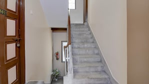 Un escalier avec une rampe en bois, un extincteur et une porte avec une plaque numérotée.