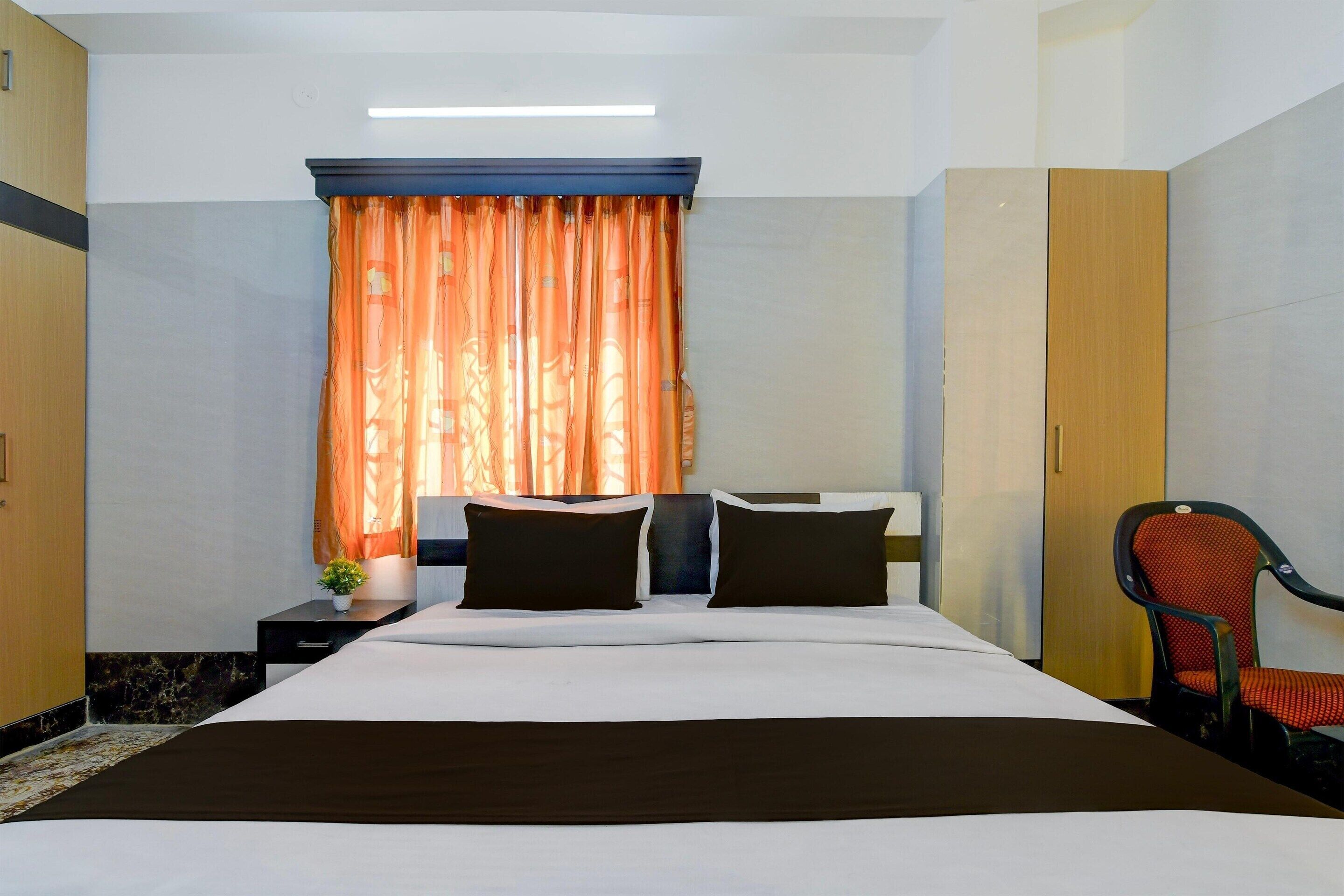 Una camera d'albergo con un letto, un comodino, una sedia e un armadio.