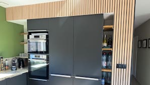 Et moderne køkken med indbyggede hårde hvidevarer, en væg med trælameller og en vanddispenser.