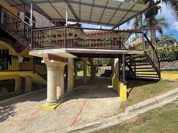 A covered outdoor area with a staircase, columns, and a railing.