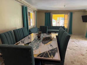 A dining area with a marble table, green upholstered chairs, and a sofa. - Segundo Piso Completó (Pedro Brand)