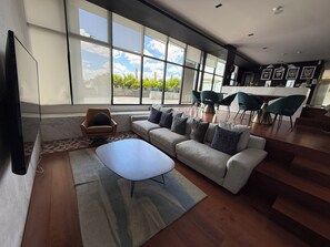 Ein modernes Wohnzimmer mit einem Ecksofa, einem Couchtisch und einem Essbereich mit Stühlen.