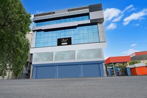 A modern building with a glass facade, a company-serviced sign, and a blue garage door. - Deluxethe Serene Woods Malkajgiri (Hyderabad)