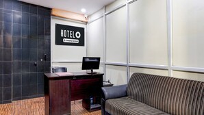 A hotel room with a desk, a computer, a sofa, a ceiling fan, and a large window. - Deluxe Sai Nivas Rushikonda (Visakhapatnam)