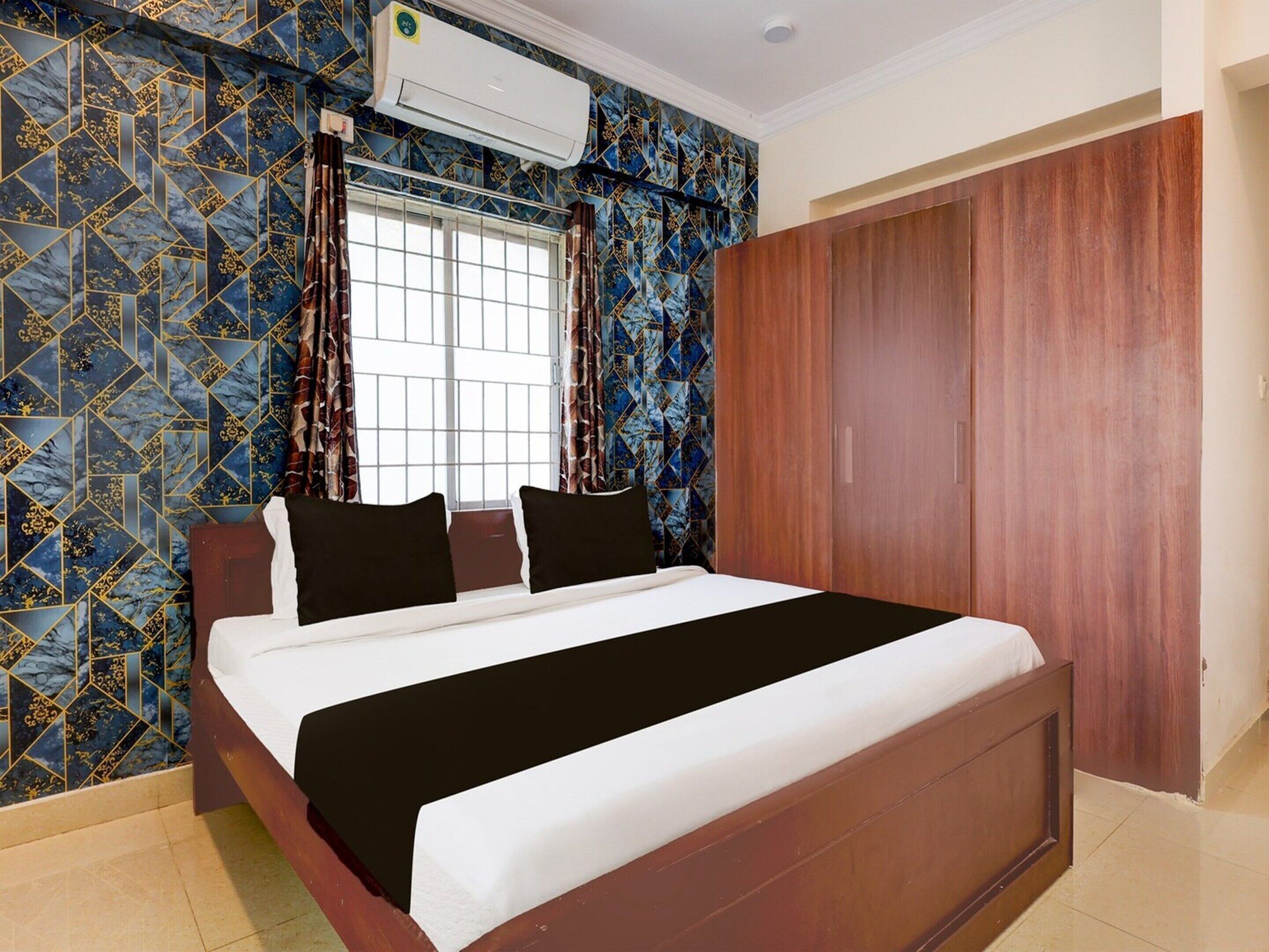 A bedroom with a bed, a window with curtains, an air conditioning unit, and a wardrobe.
