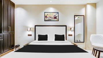 Habitación de hotel con una cama grande, un armario, un cuadro, un espejo y una silla blanca.