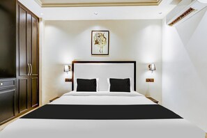 A hotel room with a large bed, a wardrobe, a framed artwork on the wall, and two bedside lamps. - Classic With Balcony Cloud Bay (Gurugram)