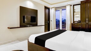 A hotel room with a bed, a TV mounted on the wall, a balcony with curtains, and a ceiling fan. - Classic With Balcony Cloud Bay (Gurugram)