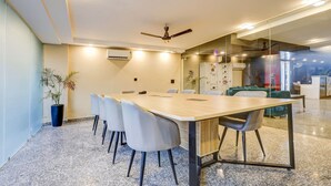 Ein moderner Konferenzraum mit langem Tisch, Stühlen, Deckenventilator und Glastrennwand.