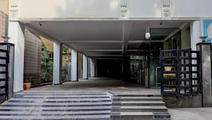 A building entrance with steps leading up to a covered area, a gate, and a clock. - Deluxe Benz Circle MG Road (Vijayawada)