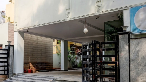 A building entrance with a set of stairs leading up to a door, a hanging light fixture, and a large blue sign. - Deluxe Benz Circle MG Road (Vijayawada)