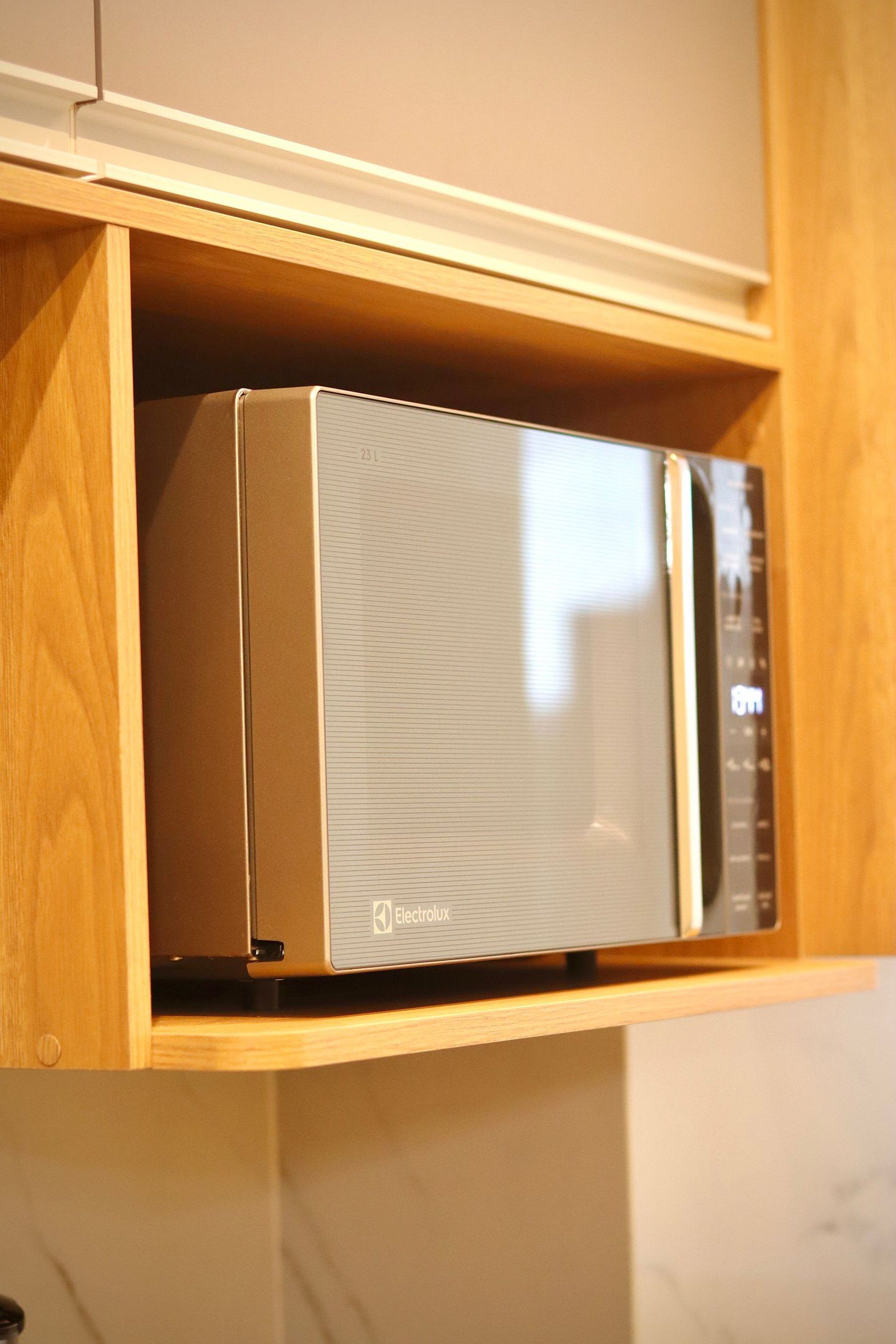 A microwave in a wooden cabinet.