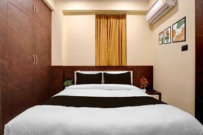 A hotel room with a bed, a nightstand, a potted plant, and a wall-mounted air conditioner. - Classic With Balcony Chandrashila Residency (Patna)